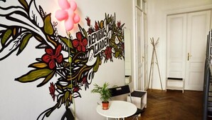 Una habitación con un mural de un jardín, una mesa redonda con sillas y una puerta al fondo.