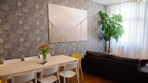 Un comedor con una mesa y sillas, un sofá, y un cuadro grande en la pared.