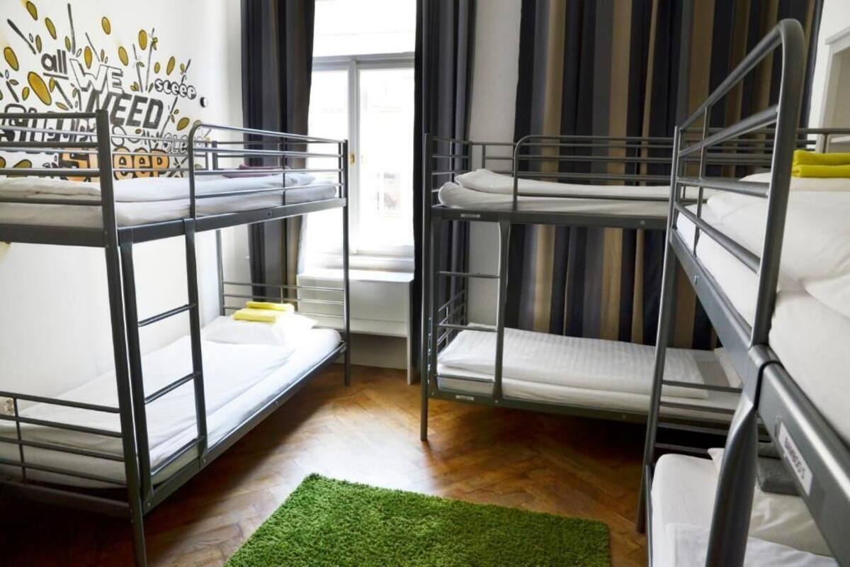 A dormitory room with bunk beds, a green rug, and a motivational poster on the wall.