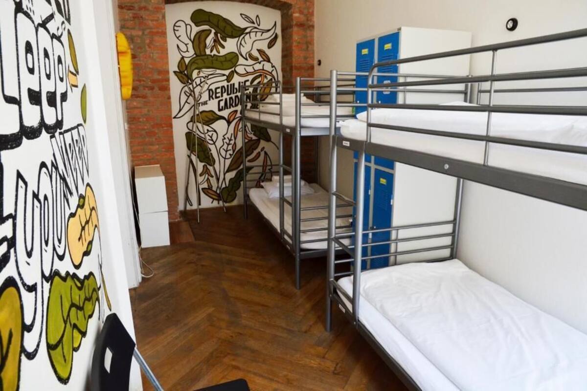 A dormitory room with bunk beds, a mural on the wall, and a small desk.