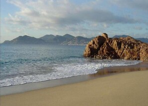 Ein Strand mit Felsen und ruhiger See.