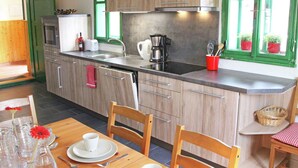 Una cocina moderna con armarios de madera, un lavamanos de acero inoxidable y un comedor con una mesa dispuesta para dos.