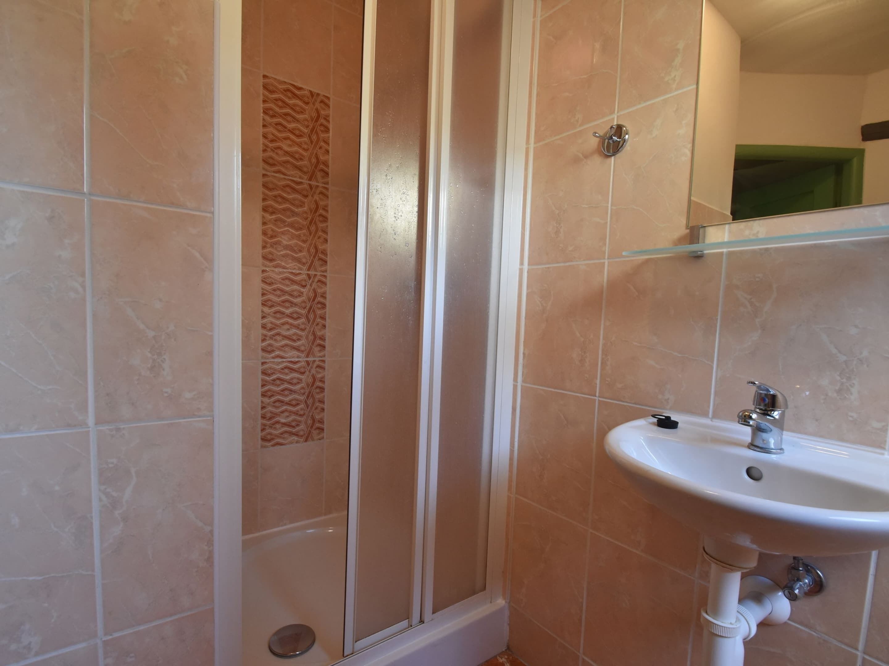 A bathroom with a shower, a sink, and a mirror.
