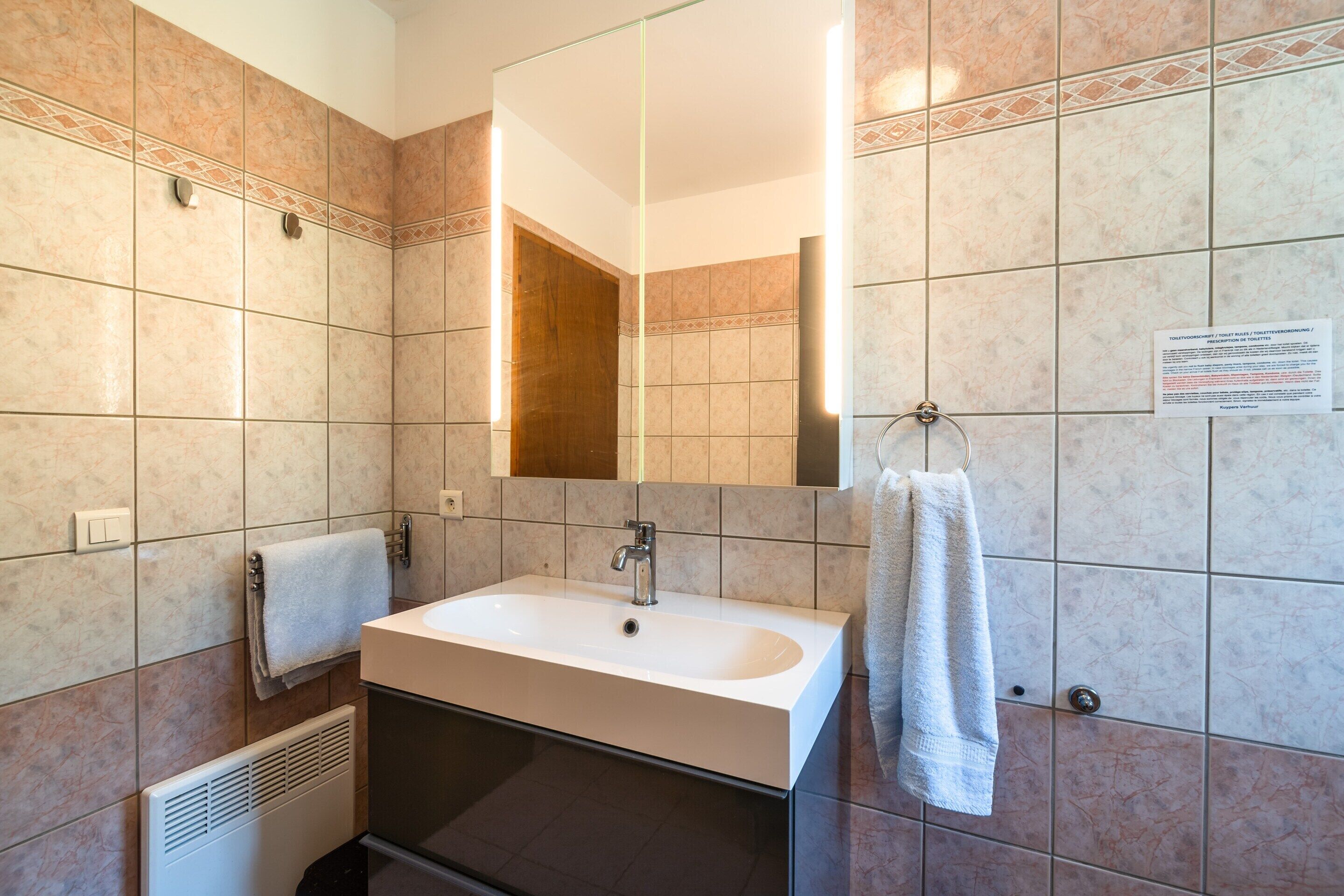 A bathroom with a sink, mirror, towel rack, and a vent.