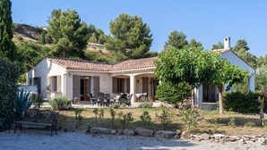 Una casa de dos pisos con un patio, mobiliario exterior y un jardín.