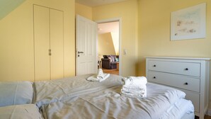 A bedroom with a bed, a dresser, and a door leading to another room.