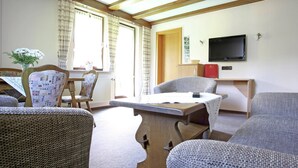 A cozy living room with a wooden ceiling, a television, and a dining area with a table and chairs. - Charming Apartment With Balcony, Garden, BBQ, Parking, Heating (Schmallenberg)