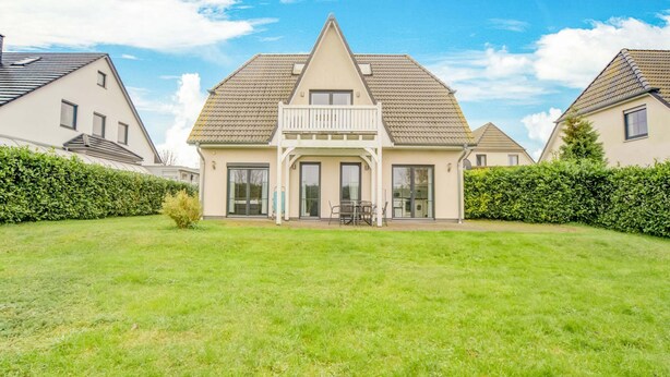 Une maison à deux étages avec une grande pelouse devant, un balcon et un garage.