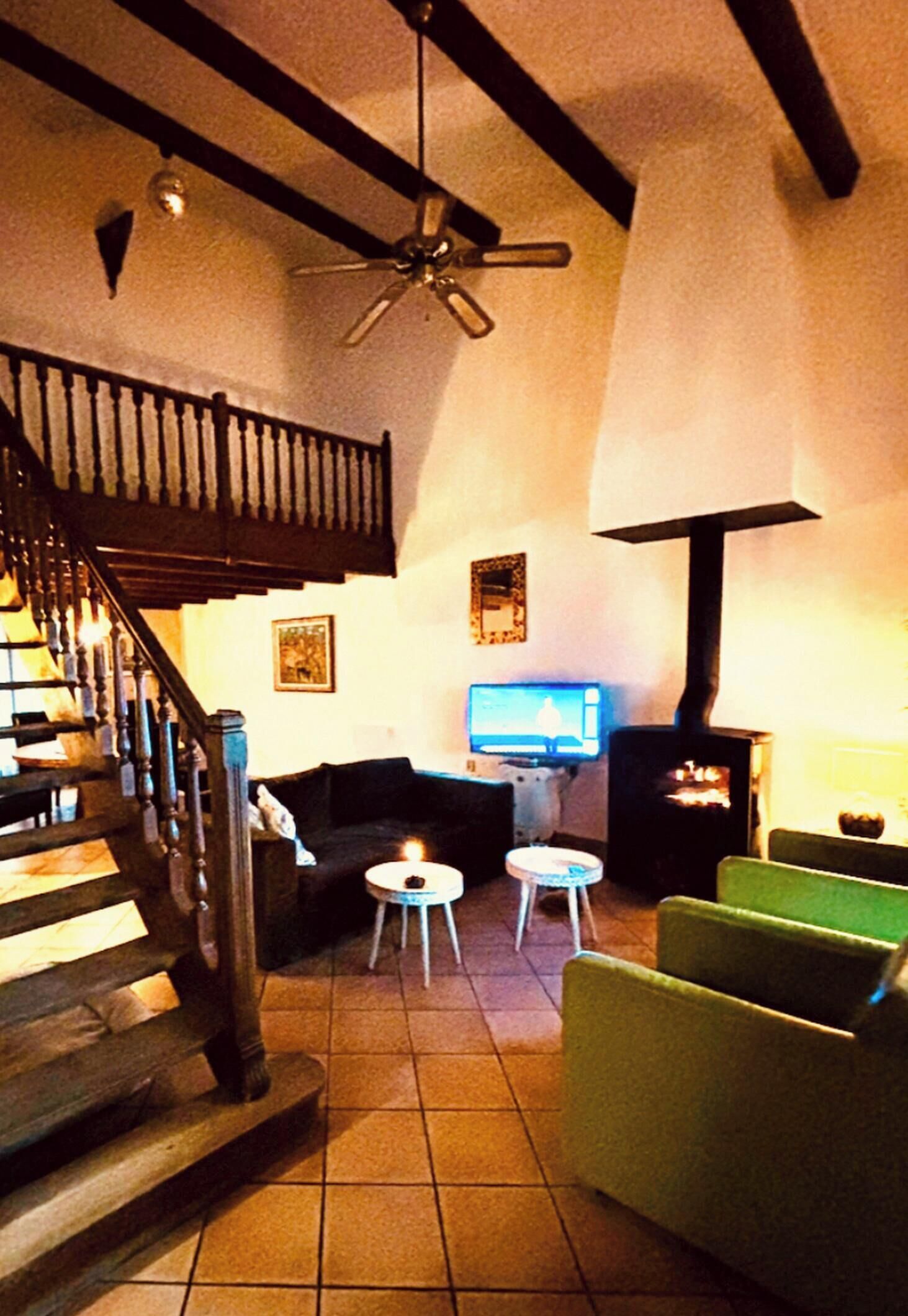 Un salon avec un escalier, un téléviseur, une cheminée et un ventilateur de plafond.