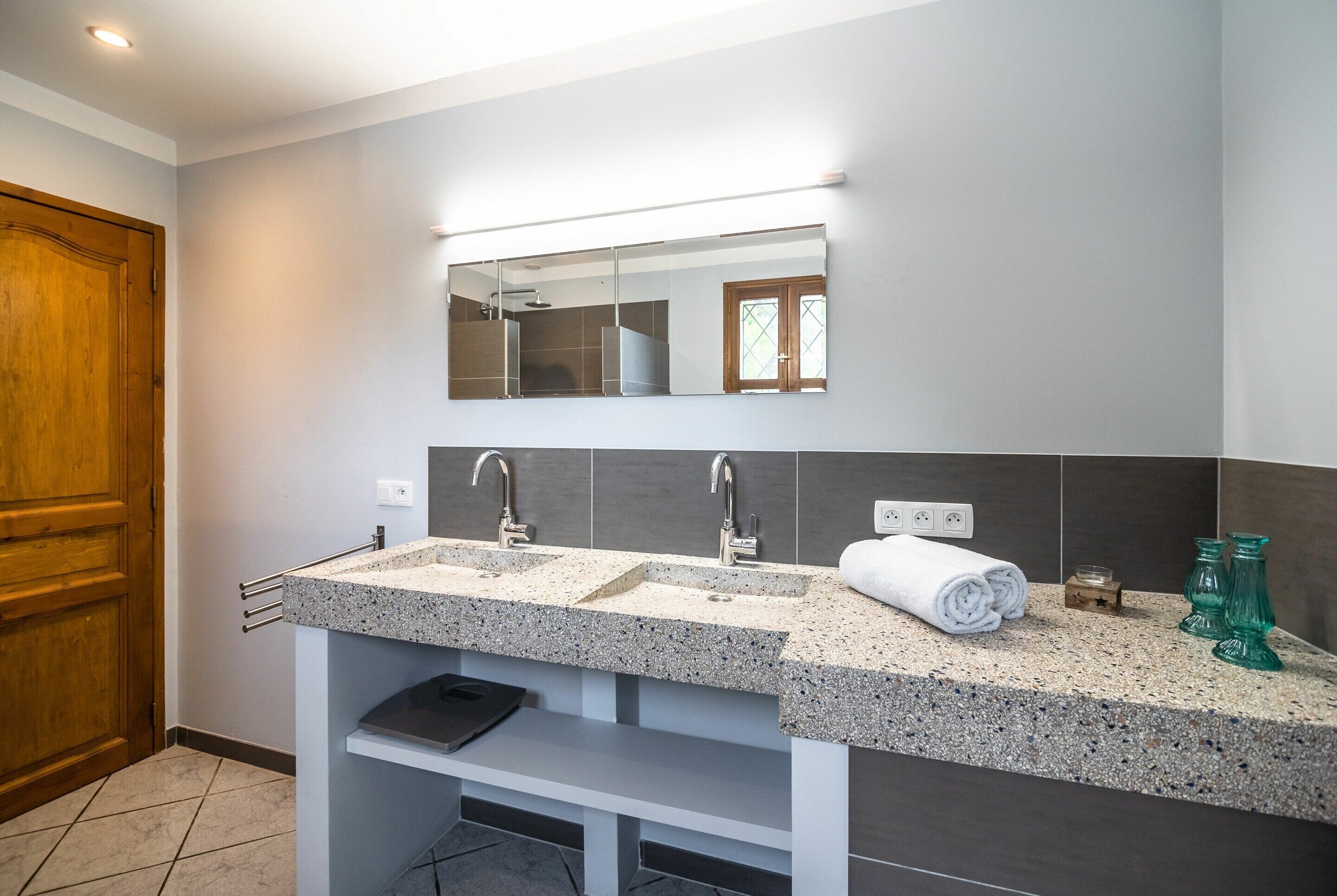 A bathroom with two sinks, a mirror, and a towel rack.