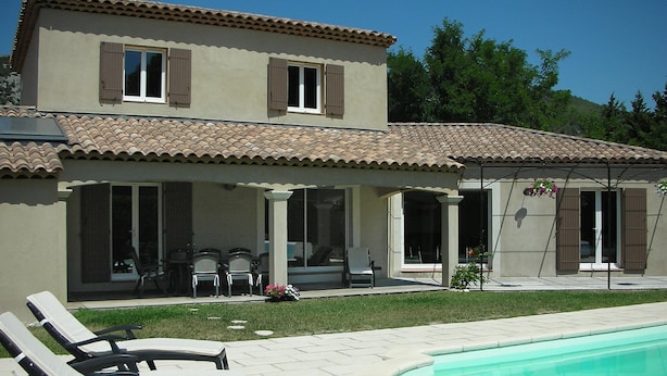 Ein zweistöckiges Haus mit Swimmingpool, Außenbereich zum Sitzen und einer überdachten Terrasse.