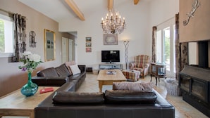 A living room with a sofa set, a television, a fireplace, and a chandelier. - Stylish Family Villa in Felines (Boutenac)