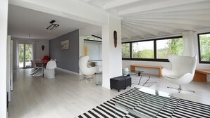 A spacious living area with a large window, a dining table, and modern furniture. - Villa in Malves Near Carcassonne Pool (Malves-en-Minervois)