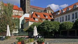 A courtyard with stone paving, outdoor seating, and a historic building with a tower. - Geraumiger Aufenthalt auf Mehreren Ebenen (Thale)