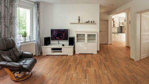 A modern living room with a leather chair, a flat-screen TV, a white cabinet, and a wooden floor. - Geraumiger Aufenthalt auf Mehreren Ebenen (Thale)