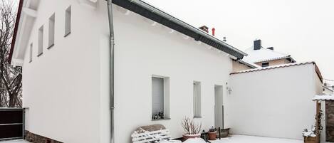 A white building with a sloped roof, a chimney, and a small attached structure.