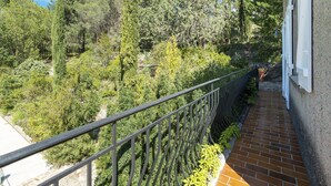 A balcony with a metal railing overlooking a garden with various trees and shrubs. - Lovely Country House With Private Pool (Vieussan)