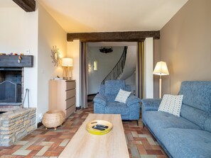 Ein Wohnzimmer mit Kamin, einer Couch, einem Couchtisch und einer Treppe, die in einen anderen Raum führt.