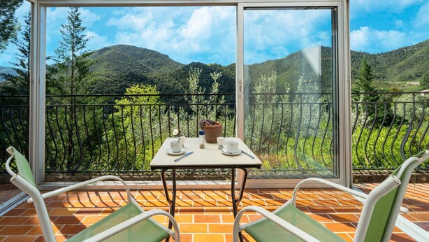 A balcony with a table and chairs, overlooking a mountainous landscape. - Lovely Country House With Private Pool (Vieussan)
