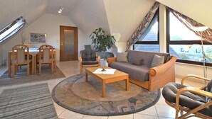A spacious loft with a high ceiling, a dining area with wooden chairs, a sofa, and a coffee table.