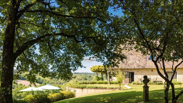 Un bâtiment en pierre doté d’un jardin, d’une statue et offrant une vue sur la campagne.