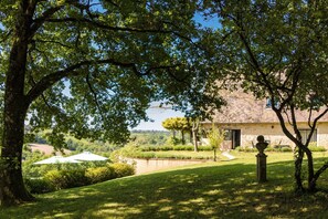 Un bâtiment en pierre doté d’un jardin, d’une statue et offrant une vue sur la campagne.