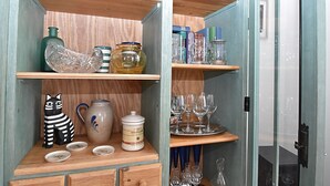 A wooden shelf unit with various glassware and ceramic items.