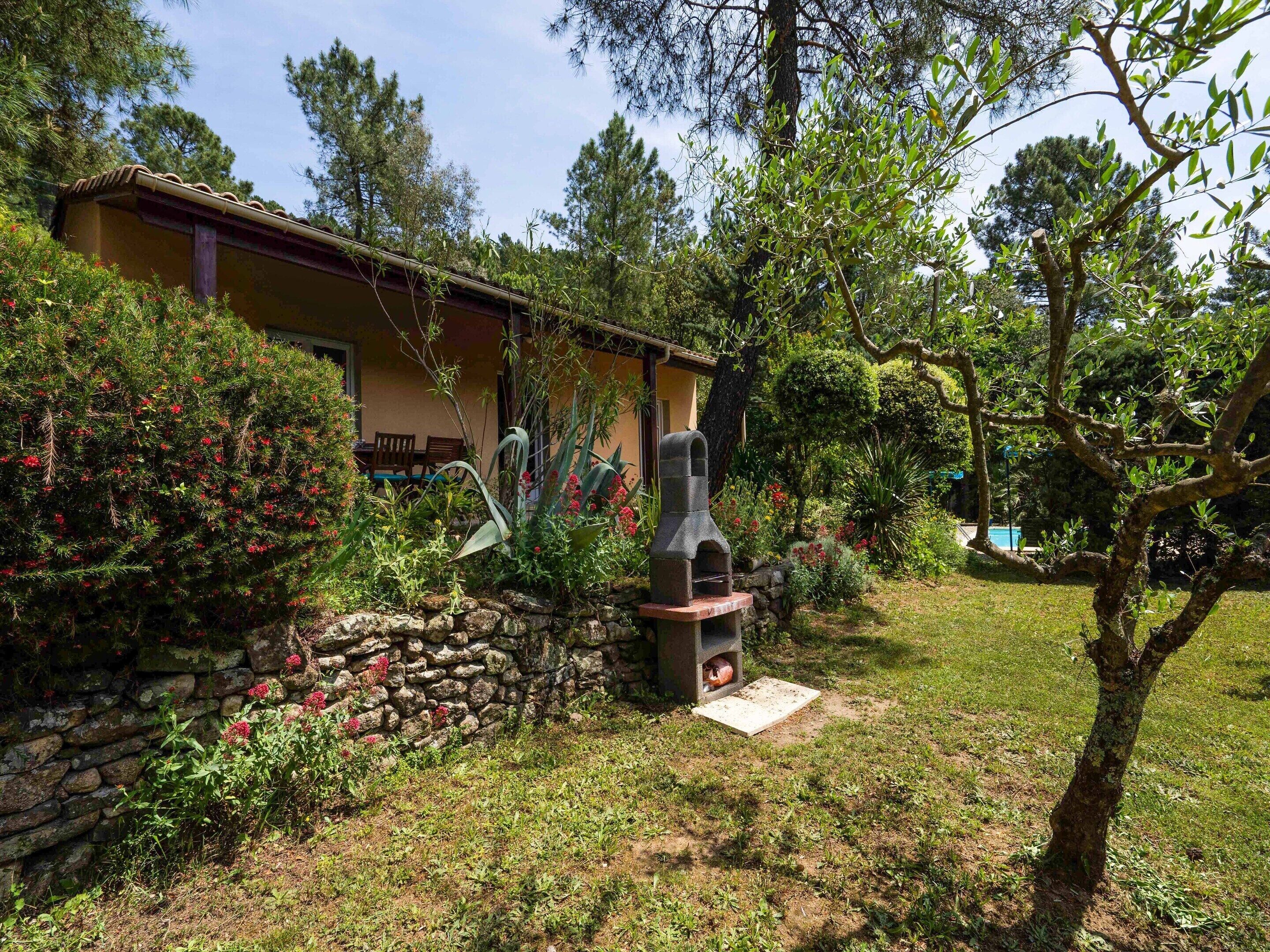 Une maison avec un mur en pierre, un barbecue et une piscine à l’arrière-plan.