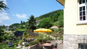 A patio with a table and chairs, a yellow umbrella, and a stone wall. - Quaint Apartment with Balcony in Bad Pyrmont near River (Bad Pyrmont)