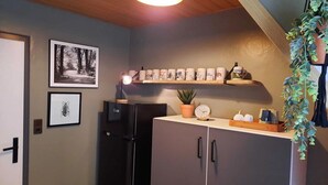 A compact kitchen with a black refrigerator, a wooden ceiling, and a shelf with decorative items. - Spacious Apartment in Rattlar near Forest (Willingen)