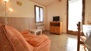 Ein Zimmer mit einem Bett, einem kleinen Tisch, einem Fernseher und einem Holzschrank.