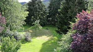 A lush garden with various trees and shrubs, a clear path, and a view of distant hills. - Comfortable Holiday Home in Quiet (Balesfeld)