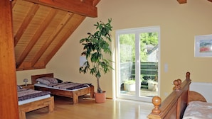 A bedroom with two wooden beds, a potted plant, and a sliding glass door leading to a balcony. - Comfortable Holiday Home in Quiet (Balesfeld)