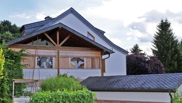 A two-story house with a sloped roof, wooden beams, and large windows. - Comfortable Holiday Home in Quiet (Balesfeld)