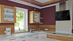 A modern kitchen with white cabinets, a built-in oven, and a window with a view of greenery. - Comfortable Holiday Home in Quiet (Balesfeld)