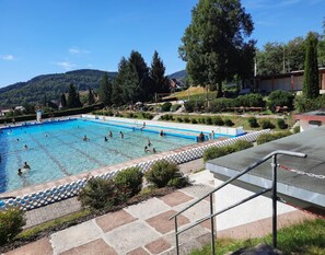 Una piscina rodeada de zonas ajardinadas, con escalones que bajan hacia ella.