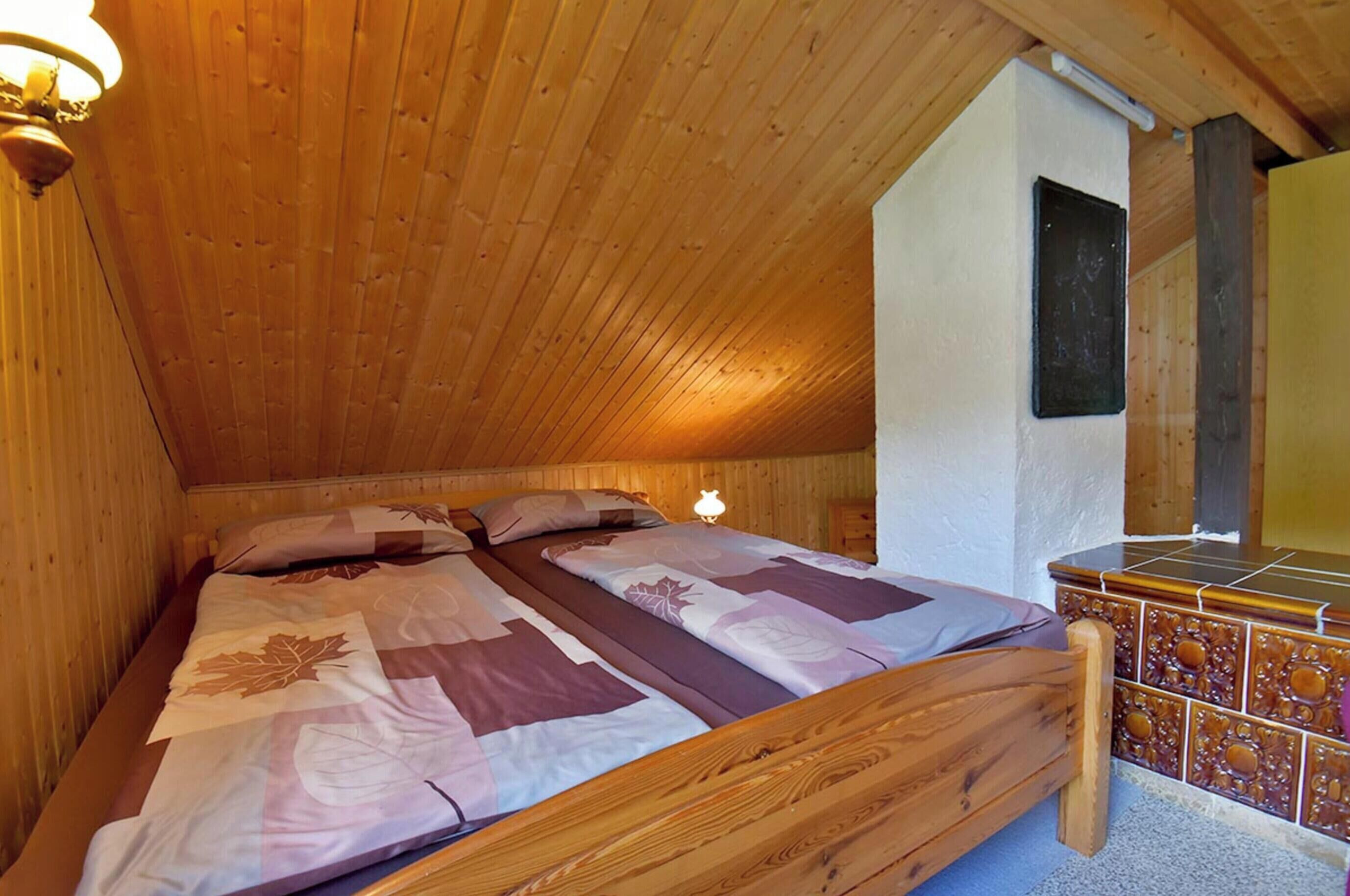 A wooden bunk bed with a leaf-patterned bedspread, a bedside lamp, and a tiled cabinet.