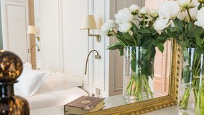 A hotel room with a bed, a mirror, and two vases with flowers. - Villas Foch (Bordeaux)