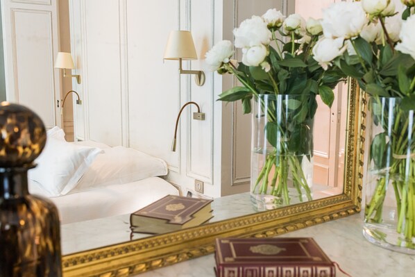 A hotel room with a bed, a mirror, and two vases with flowers. - Villas Foch (Bordeaux)