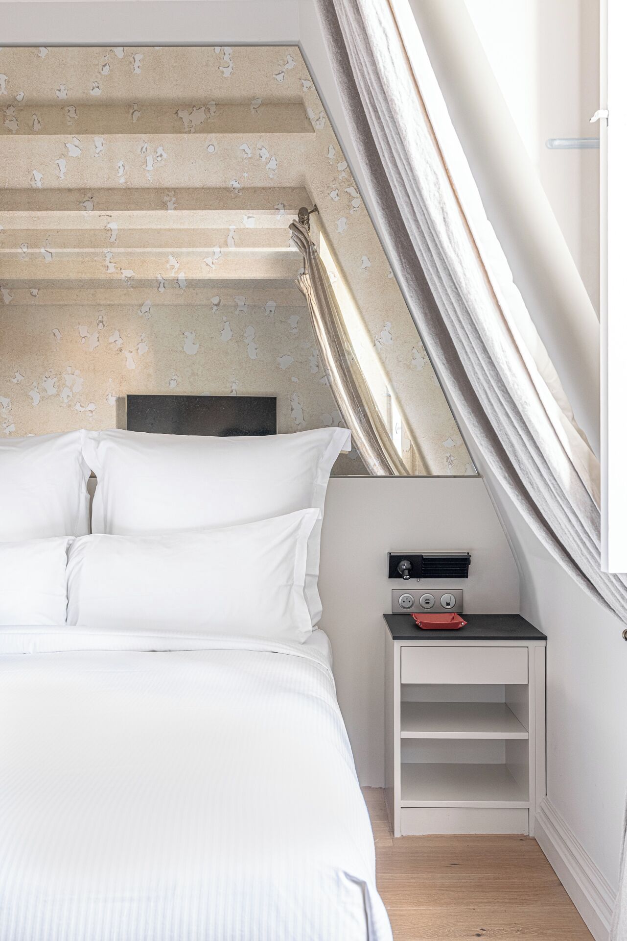 Un dormitorio con cama, mesita de noche, calefactor y ventana con cortinas.