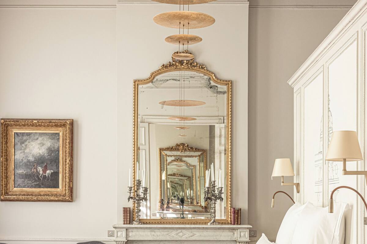 Quarto com cama grande, lareira, espelho e lustre.