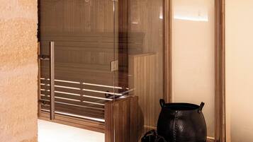A modern interior with a wooden ceiling, a glass door leading to a sauna area, and two black leather bags on the floor.