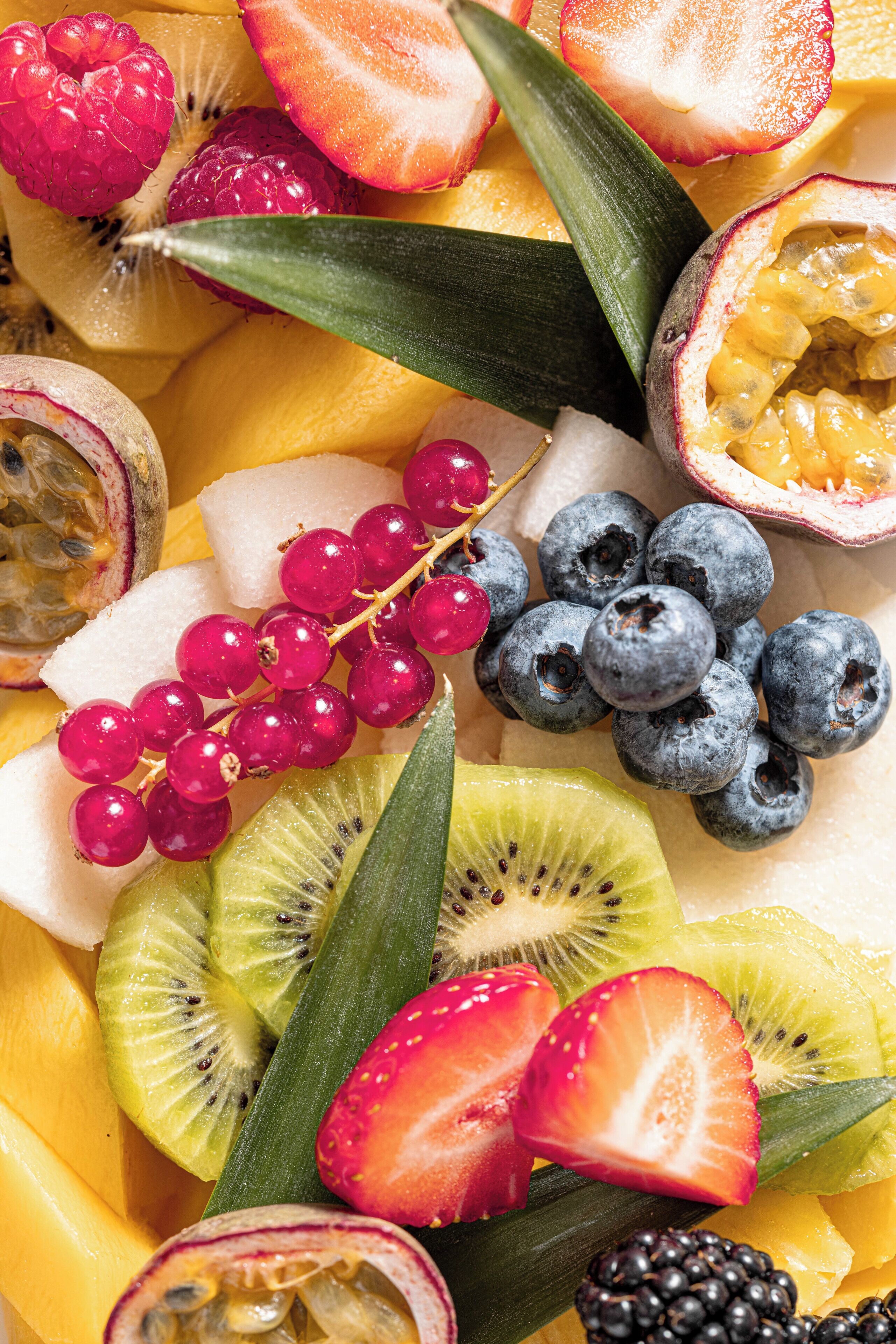 Une variété de fruits et de légumes, notamment des fraises, des kiwis, des myrtilles et des fruits de la passion.
