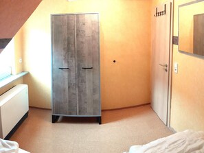 Een kamer met een kledingkast, een bed en een bureau.