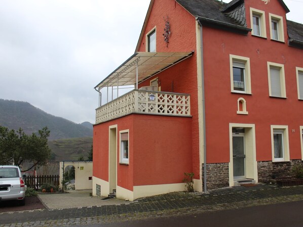 Een rood gebouw met een balkon en een auto ervoor geparkeerd.