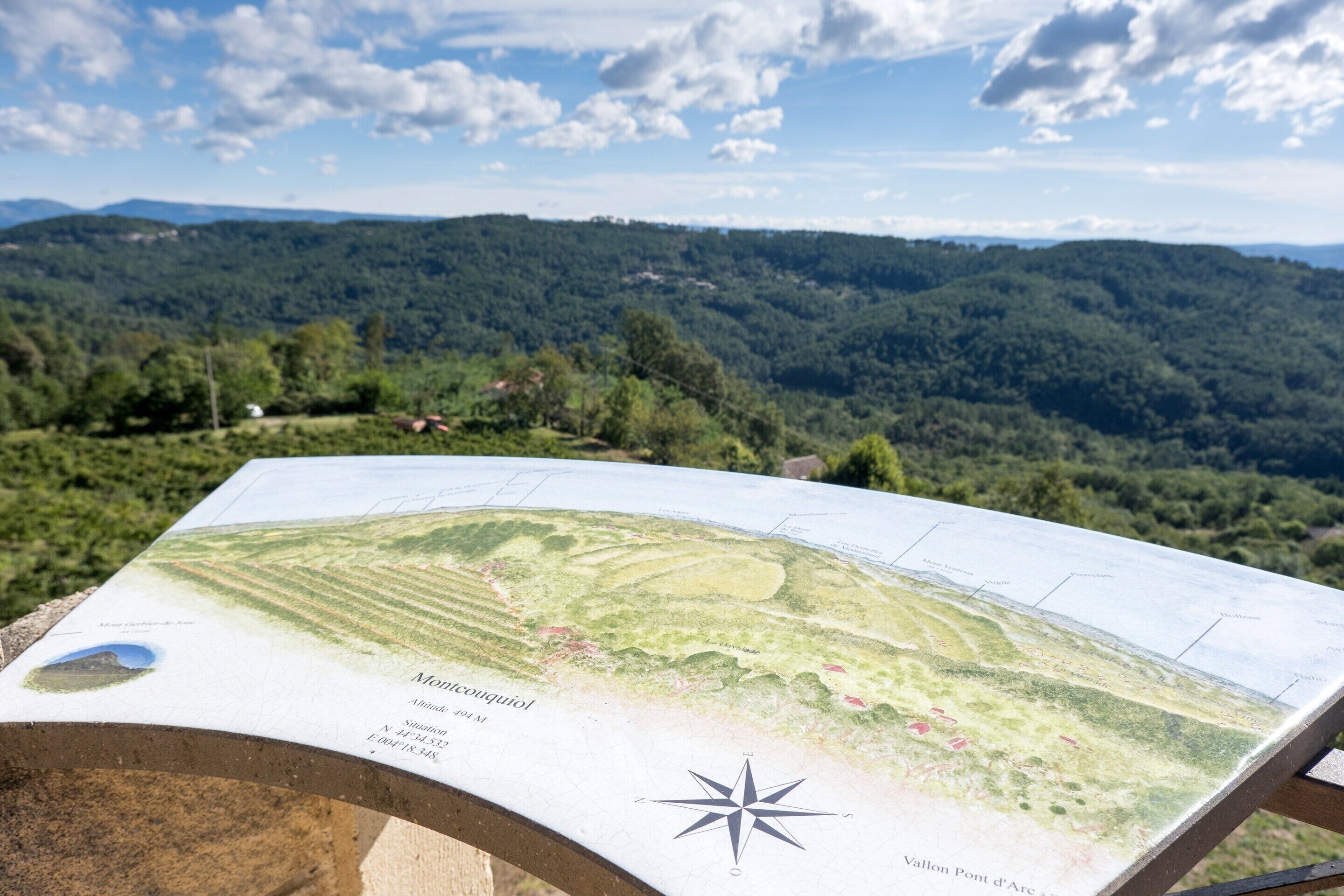 A map with a compass rose, surrounded by a mountainous landscape.