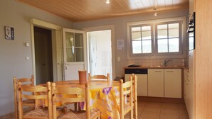 A dining area with a wooden table and chairs, a window with blinds, and a kitchen with cabinets and a sink. - Quiet Holiday Home in Les Vans With Pool (Les Vans)