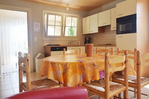 A kitchen with white cabinets, a stove, and a dining table with chairs. - Quiet Holiday Home in Les Vans With Pool (Les Vans)