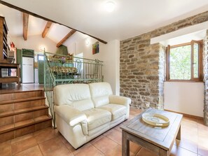 A living room with a sofa, a dining table, a staircase, and a kitchen area. - Relaxing Stay in Les Vans (Les Vans)