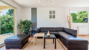 A modern living room with a black leather sectional sofa, a small table, and a potted plant. - Charming Villa Near Les Vans (Les Vans)